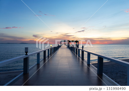 Walkway extending into calm sea at twilight. 131998490