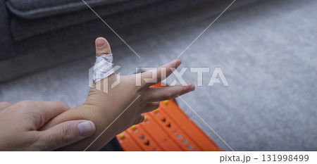 The child has a cut wound covered with a bandage 131998499