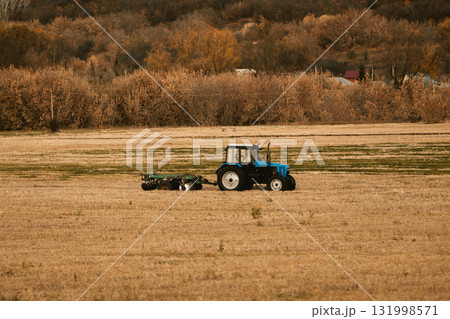 blue tractor drives across an autumn field, copy space 131998571