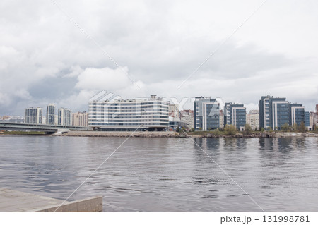 Riverside development in St. Petersburg showcases modern buildings by the water, blending urban design with nature under cloudy skies. 131998781