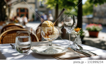 Outdoor cafe table with caramel ice cream, water glass, and cutlery in summer Outdoor cafe table with caramel ice cream, water glass, and cutlery in summer 131999234