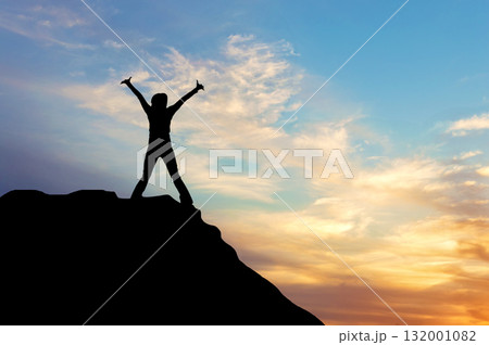 Silhouette of a happy man on the top of a mountain at sunset 132001082