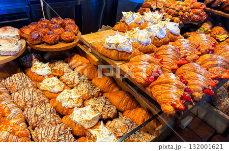 Golden flaky croissants and pastry sweets with toppings displayed on bakery store showcase. Delicious food to go. Golden flaky croissants and pastry sweets with toppings displayed on bakery store showcase. Delicious food to go. 132001621
