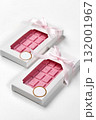 Two pink chocolate bars wrapped with pink ribbon in white box on white background 132001967