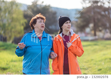 Family outdoor vacation. Portraits of grandmother and granddaughter walking together in the spring park. International Day of Older Persons Family outdoor vacation. Portraits of grandmother and granddaughter walking together in the spring park. International Day of Older Persons 132002078