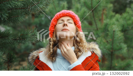 Sick exhausted woman suffering from acute sore in throat flu, touches neck with hand outdoor in park 132002092