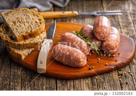 Photo of italian sausage salsiccia on cutting board on wooden table. Photo of italian sausage salsiccia on cutting board on wooden table. 132002183