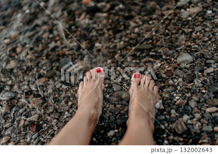 Feet water pebbles refreshing woman's bare feet in clear shallow water on a summer beach 132002643