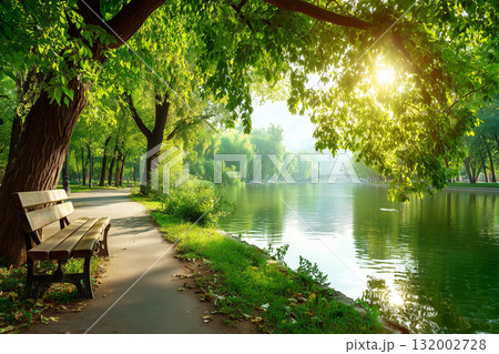 Peaceful Park Scene with Wooden Bench under Green Trees beside Calm Lake in Morning Sunlight Peaceful Park Scene with Wooden Bench under Green Trees beside Calm Lake in Morning Sunlight 132002728
