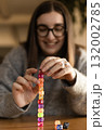 Young woman smiling and building a pyramid of dice. Concept of patience focus and achievement. 132002785