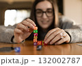 Smiling woman stacking dice into a pyramid. Concept of play learning and focus. 132002787