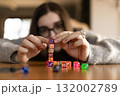 Woman carefully placing colorful dice one on another. Concept of balance patience and creativity. 132002789