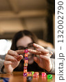 Young woman stacking dice one on another on a table. Concept of concentration and play. 132002790