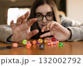 Young woman smiling while destroying a pyramid of dice. Concept of play fun and imperfection. 132002792