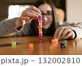 Colorful dice falling and scattering on the table in front of a young woman. Fun and dynamic play concept. 132002810
