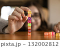 Smiling woman knocking down a column of colorful dice. Concept of play spontaneity and joy. 132002812