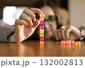 Close up of a woman building a column of dice on a table. Concentration and patience theme. 132002813