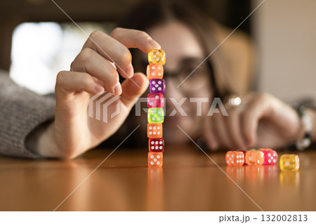 Close up of a woman building a column of dice on a table. Concentration and patience theme. 132002813