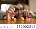 Woman stacking dice one on another on the table in front of her face. Concept of focus creativity and patience. 132002814