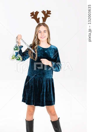 Cheerful teen girl in velvet dress brown reindeer antlers festive ornaments, celebrating holiday season on white background. Cheerful teen girl in velvet dress brown reindeer antlers festive ornaments, celebrating holiday season on white background. 132003635