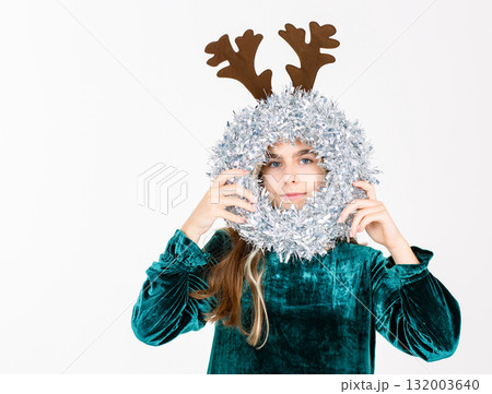 Cheerful teen girl in velvet dress brown reindeer antlers festive ornaments, celebrating holiday season on white background. Cheerful teen girl in velvet dress brown reindeer antlers festive ornaments, celebrating holiday season on white background. 132003640