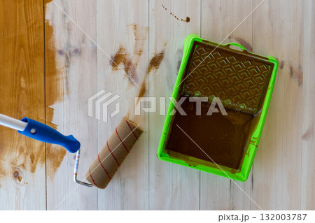 Wood staining with paint roller and tray on wooden surface Wood staining with paint roller and tray on wooden surface 132003787