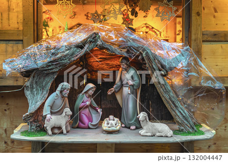 Traditional nativity scene with Joseph, Mary, baby Jesus, and animals inside a wooden manger under soft light. Concept of nativity, Christmas miracle and spiritual celebration 132004447