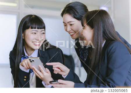 教室でクラスメイトとスマホを見ながら話す女子高生 132005065