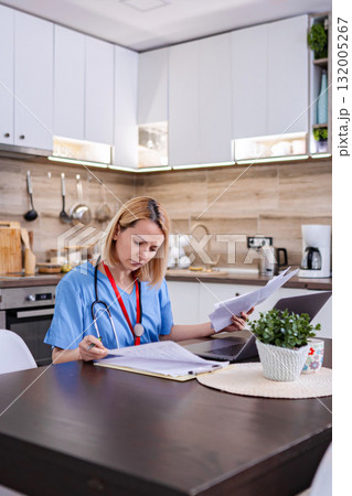Female doctor working from home checking medical records 132005267