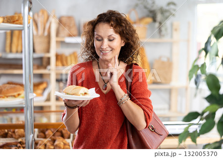 Cheerful woman with fresh sandwich in bakery 132005370
