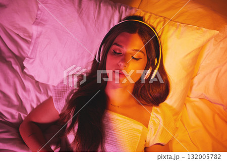 Gen z, headphones and woman sleeping with creative vaporwave lighting in a bedroom bed. Dreaming, music listening and web audio streaming of a female model resting eyes with makeup on a pillow 132005782