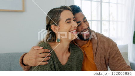 Love, smile and hug with an interracial couple on a sofa in the living room of their home together for romance. Happy, funny or laughing with a man and woman in their house to relax while bonding 132005986