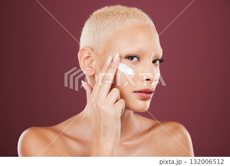 Face cream, portrait and beauty skincare of woman in studio isolated on red background. Dermatology aesthetic, cosmetics and young female model apply lotion, creme or moisturizer for facial treatment Face cream, portrait and beauty skincare of woman in studio isolated on red background. Dermatology aesthetic, cosmetics and young female model apply lotion, creme or moisturizer for facial treatment 132006512