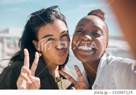 Woman, friends and smile with peace sign for selfie, profile picture or vlog at the beach for summer vacation. Portrait of happy women smiling for photo memory, friendship or joy by the ocean coast Woman, friends and smile with peace sign for selfie, profile picture or vlog at the beach for summer vacation. Portrait of happy women smiling for photo memory, friendship or joy by the ocean coast 132007124