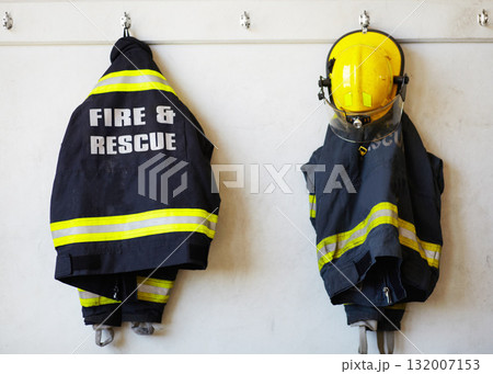 Firefighter, uniform and clothing hanging on wall rack at station for fire fighting protection. Fireman gear, rescue jacket and helmet with reflector for emergency services, equipment or department 132007153