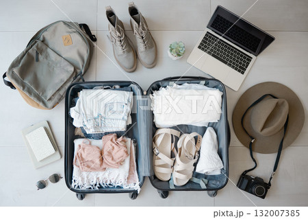 Travel, suitcase and laptop with camera for vacation or holiday with online booking on floor. Above luggage, clothes and shoes while planning for summer photography journey motivation or inspiration Travel, suitcase and laptop with camera for vacation or holiday with online booking on floor. Above luggage, clothes and shoes while planning for summer photography journey motivation or inspiration 132007385
