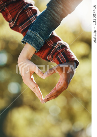 Love, care and hands of a couple in a heart for support, diversity and trust in nature. Emoji, marriage and gesture from a man and woman showing emotion, romance and affection on valentines day 132007416