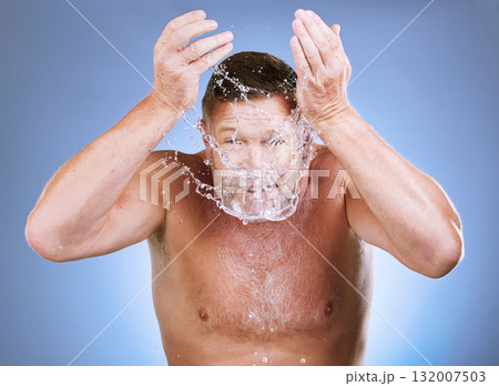 Man, water splash and face wash for skincare hygiene or natural sustainability against a blue studio background. Male washing for clean health and wellness in self love or care for facial treatment 132007503