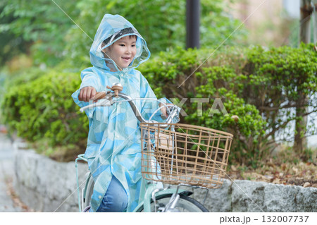 雨の日にレインコートを着て自転車に乗る子供 雨の日にレインコートを着て自転車に乗る子供 132007737