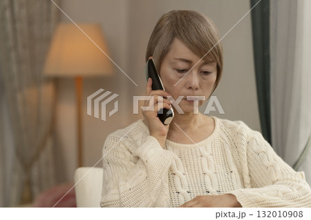 家の電話にかかってきた不信な電話に対応するシニア女性 132010908