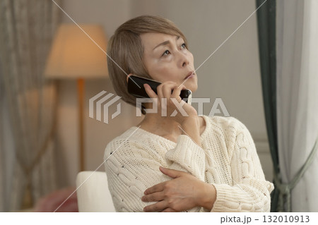 家の電話にかかってきた不信な電話に対応するシニア女性 132010913