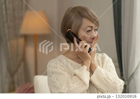 家の電話にかかってきた不信な電話に対応するシニア女性 132010916