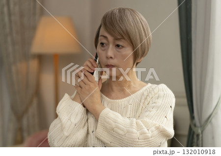家の電話にかかってきた不信な電話に対応するシニア女性 家の電話にかかってきた不信な電話に対応するシニア女性 132010918