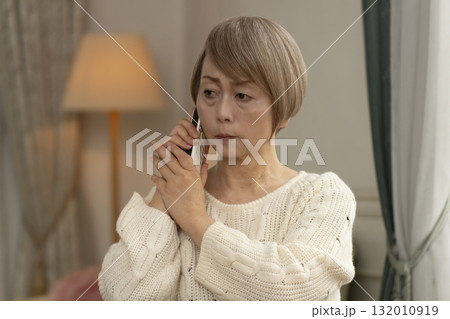家の電話にかかってきた不信な電話に対応するシニア女性 家の電話にかかってきた不信な電話に対応するシニア女性 132010919