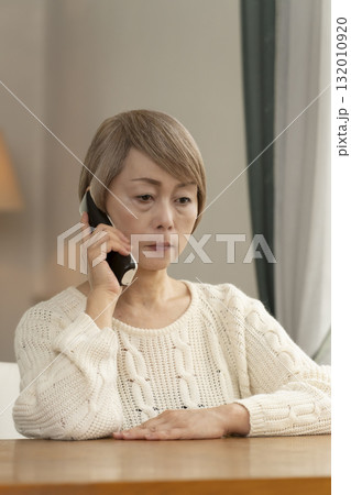 家の電話にかかってきた不信な電話に対応するシニア女性 家の電話にかかってきた不信な電話に対応するシニア女性 132010920