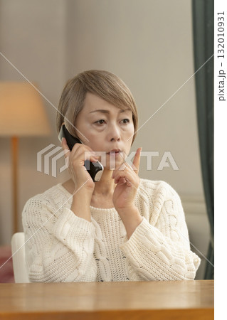 家の電話にかかってきた不信な電話に対応するシニア女性 132010931