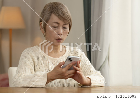 携帯電話にかかってきた不信な電話に対応するシニア女性 132011005