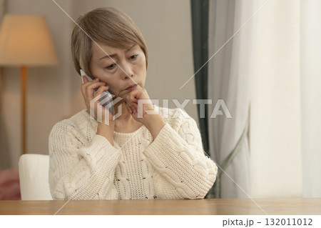 携帯電話にかかってきた不信な電話に対応するシニア女性 携帯電話にかかってきた不信な電話に対応するシニア女性 132011012