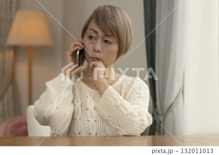 携帯電話にかかってきた不信な電話に対応するシニア女性 132011013