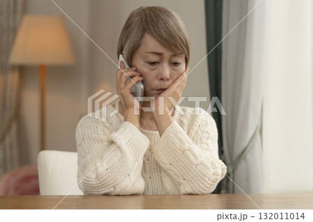 携帯電話にかかってきた不信な電話に対応するシニア女性 132011014